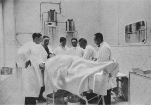 Fotograbado, igualmente publicado en Ecos Españoles de Dermatología y Sifiliografía en 1927, en el que aparece Sainz de Aja rodeado de varios colaboradores realizando una intervención quirúrgica.