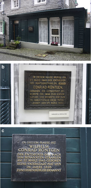 (a) Fachada de la casa natal de Roentgen con las dos placas. (b) La original, que conmemora la ciudadanía honoraria de Roentgen. (c) La que reemplaza a la inicial desde 1952.