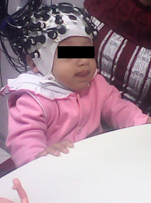 Criança de nove meses ao fazer o exame de espectroscopia (NIRS) no colo da mãe. Fonte: Arquivo pessoal, com autorização da família.