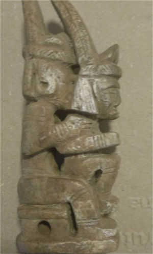 Escultura en hueso de un par de amantes heterosexuales en la típica posición de symplegma, sentada en los muslos del hombre y de espaldas a él con penetración anal de la mujer. Cultura Tairona. La escultura tiene 15.5cm de alto, 4.7cm de largo y 2.9cm de ancho.