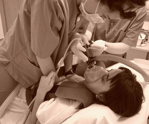 Fisioterapeuta realizando técnicas de aumento de flujo espiratorio para optimizar el desprendimiento y movilización de secreciones durante la terapia de oscilación con ayudas instrumentales.