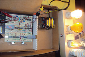 Maqueta del “Watthorímetro K0” en operación, mostrando el transformador de corriente (arriba-centro) y la carga combinada: pasiva de 25 Watts e inductiva de 23 Watts