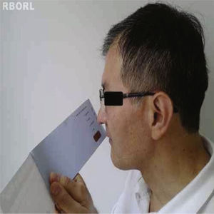 Male patient undergoing smell identification test (SIT) with booklet positioned at 1cm from the nose.