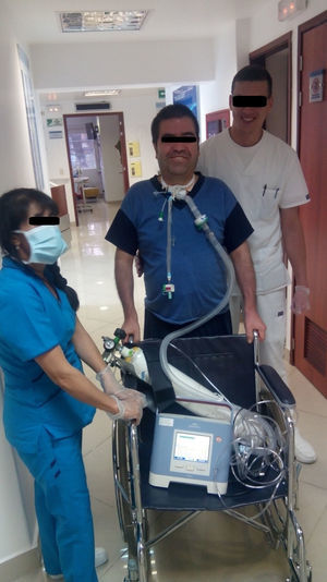 A ventilator-dependent tracheostomized patient walking with assistance from the staff.